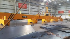 MAGBAT electro-permanent magnetic lifting beam handling a large steel plate in an industrial workshop